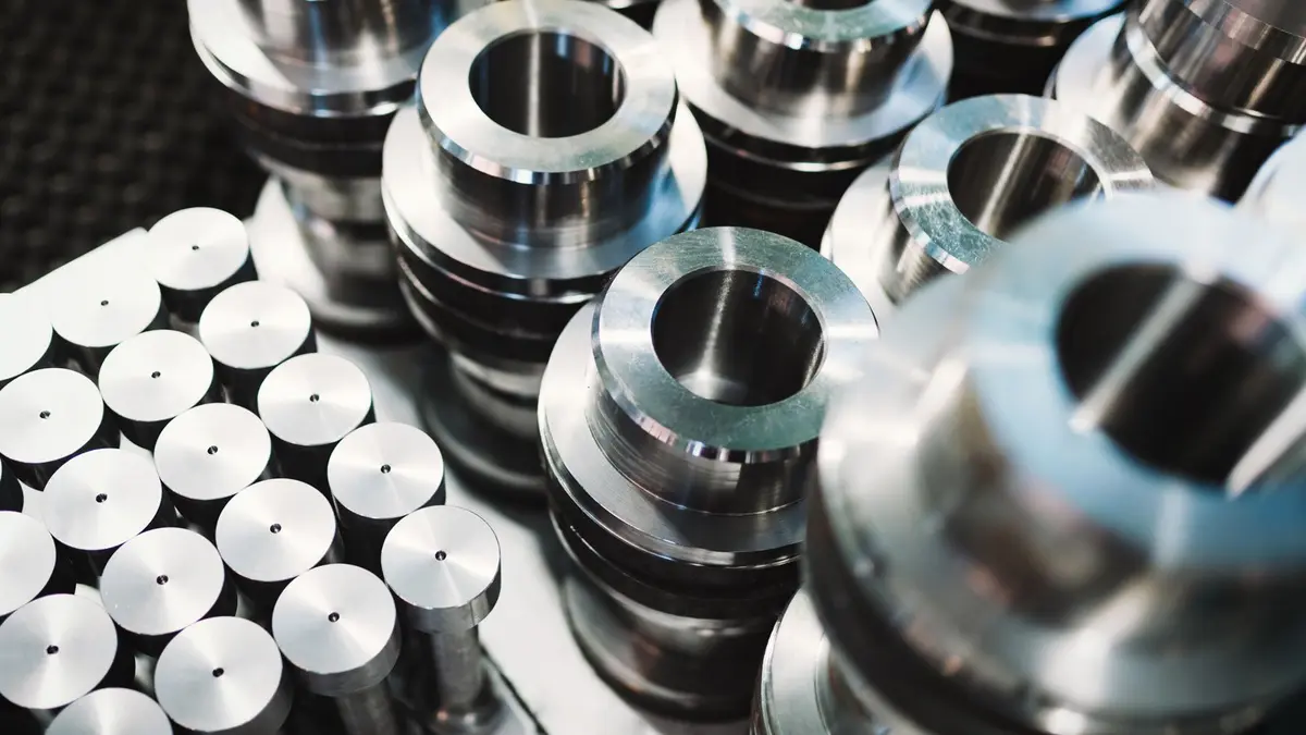 Shiny metal cylindrical components and round bars arranged closely in an industrial setting.